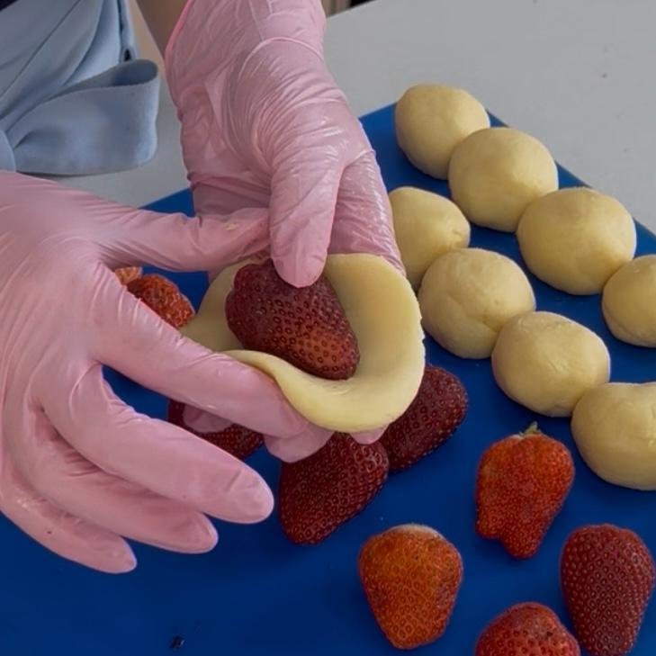 Morango sendo envolvido pelo disco de brigadeiro