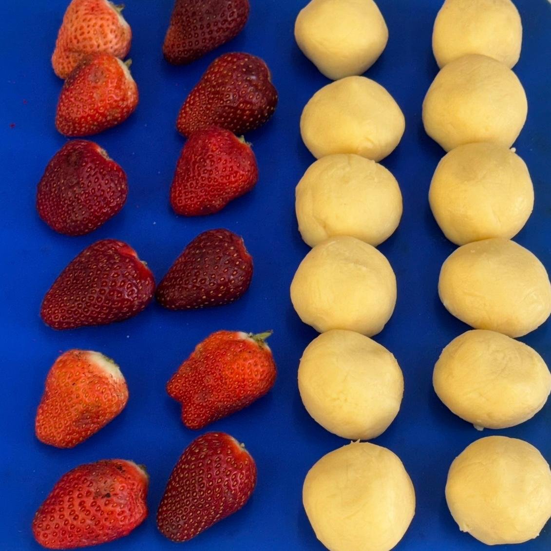 Fileiras de morangos limpos e porções de brigadeiro boleadas